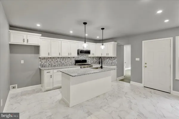 a kitchen with kitchen island a sink stainless steel appliances and white cabinets