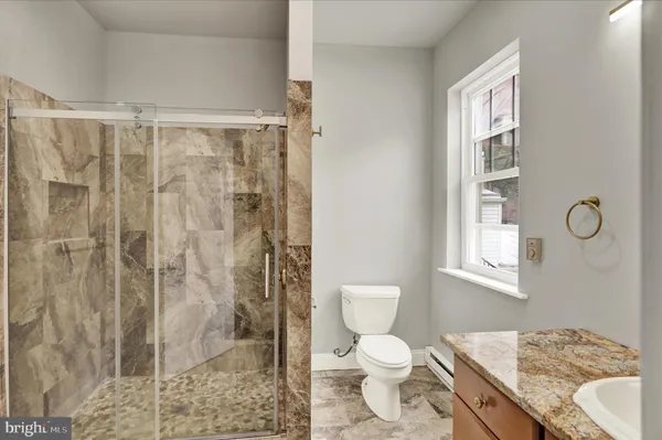 a bathroom with a granite countertop sink a toilet and shower