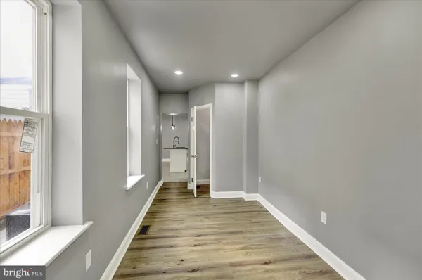 a view of a hallway with wooden floor and a bathroom