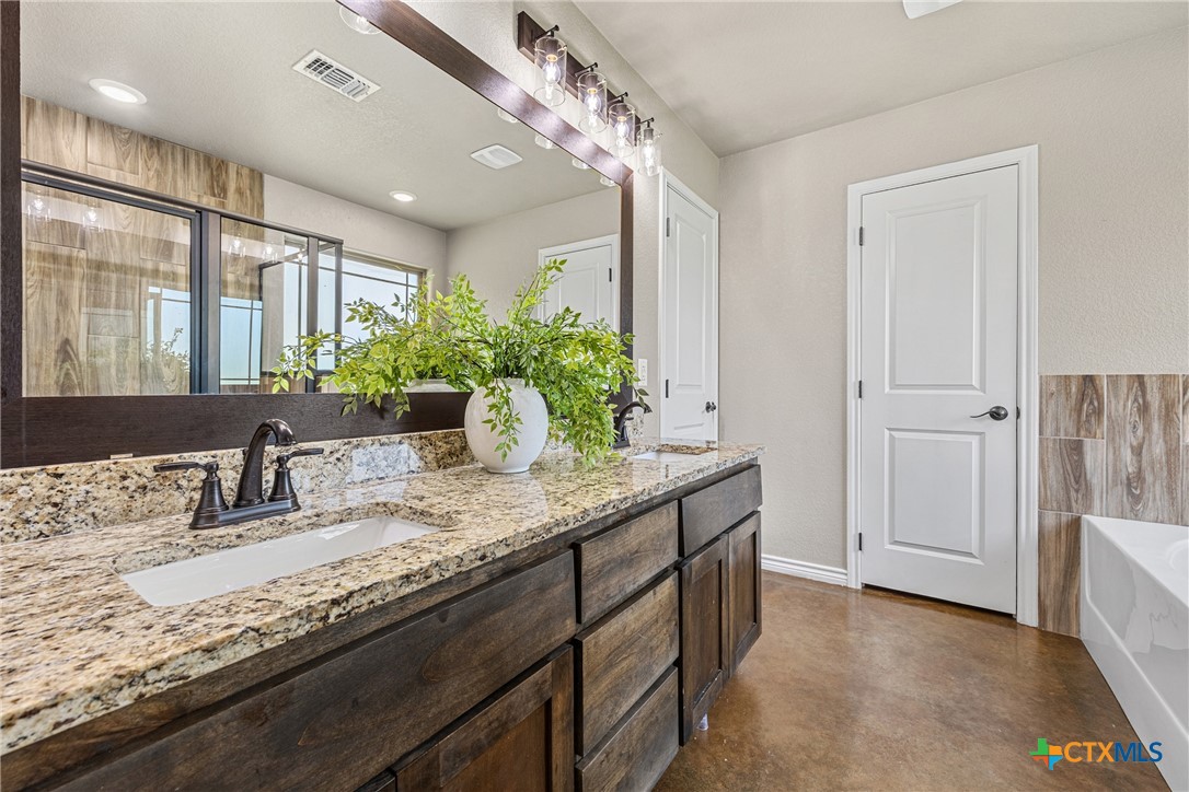 7112 Kc Ranch Court Temple, TX 76501 - Photo 19 of 30 a bathroom with a granite countertop sink a large mirror and a shower