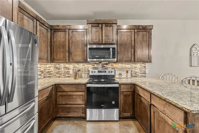 a kitchen with granite countertop a sink stove and refrigerator