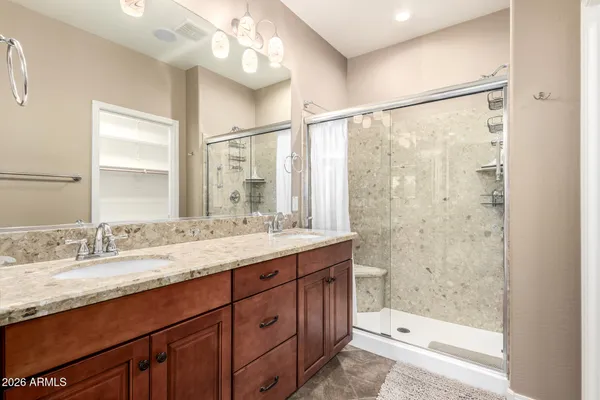 a bathroom with a granite countertop sink mirror and a shower