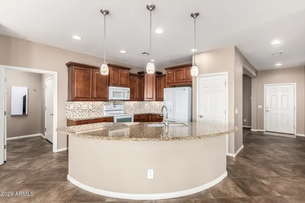 a large kitchen with granite countertop a large kitchen island a sink and a refrigerator