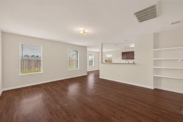 a view of an empty room with a window and wooden floor