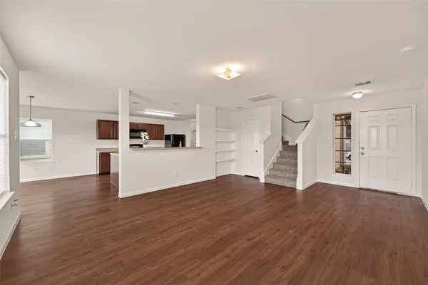 a view of a big room with wooden floor and kitchen
