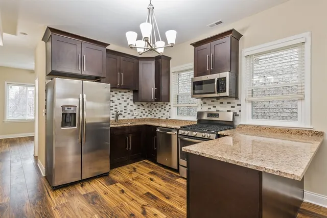 a kitchen with kitchen island granite countertop stainless steel appliances a stove top oven a sink and a refrigerator