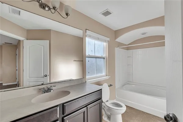 a bathroom with a bathtub shower sink vanity mirror and toilet