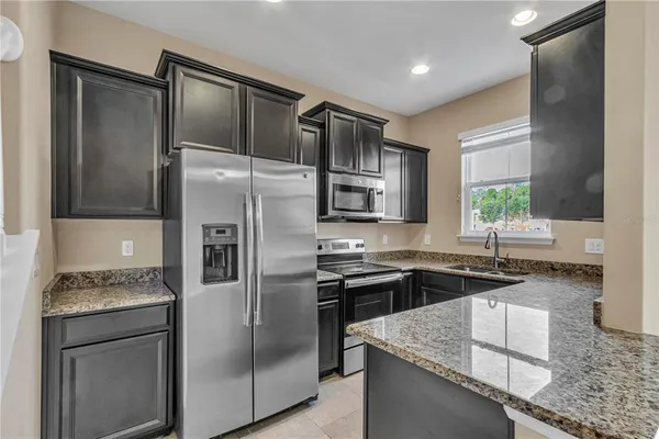 a kitchen with stainless steel appliances granite countertop a sink stove and refrigerator