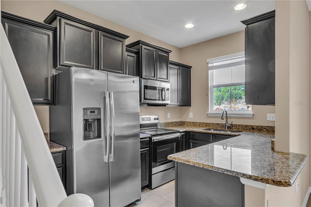 106 Carmichael Way Daytona Beach, FL 32124 - Photo 9 of 35 a kitchen with stainless steel appliances granite countertop a sink stove and refrigerator