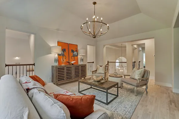 a living room with couches chandelier and a dining table with wooden floor