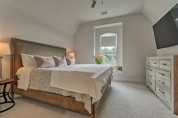 a spacious bedroom with a bed and a flat screen tv