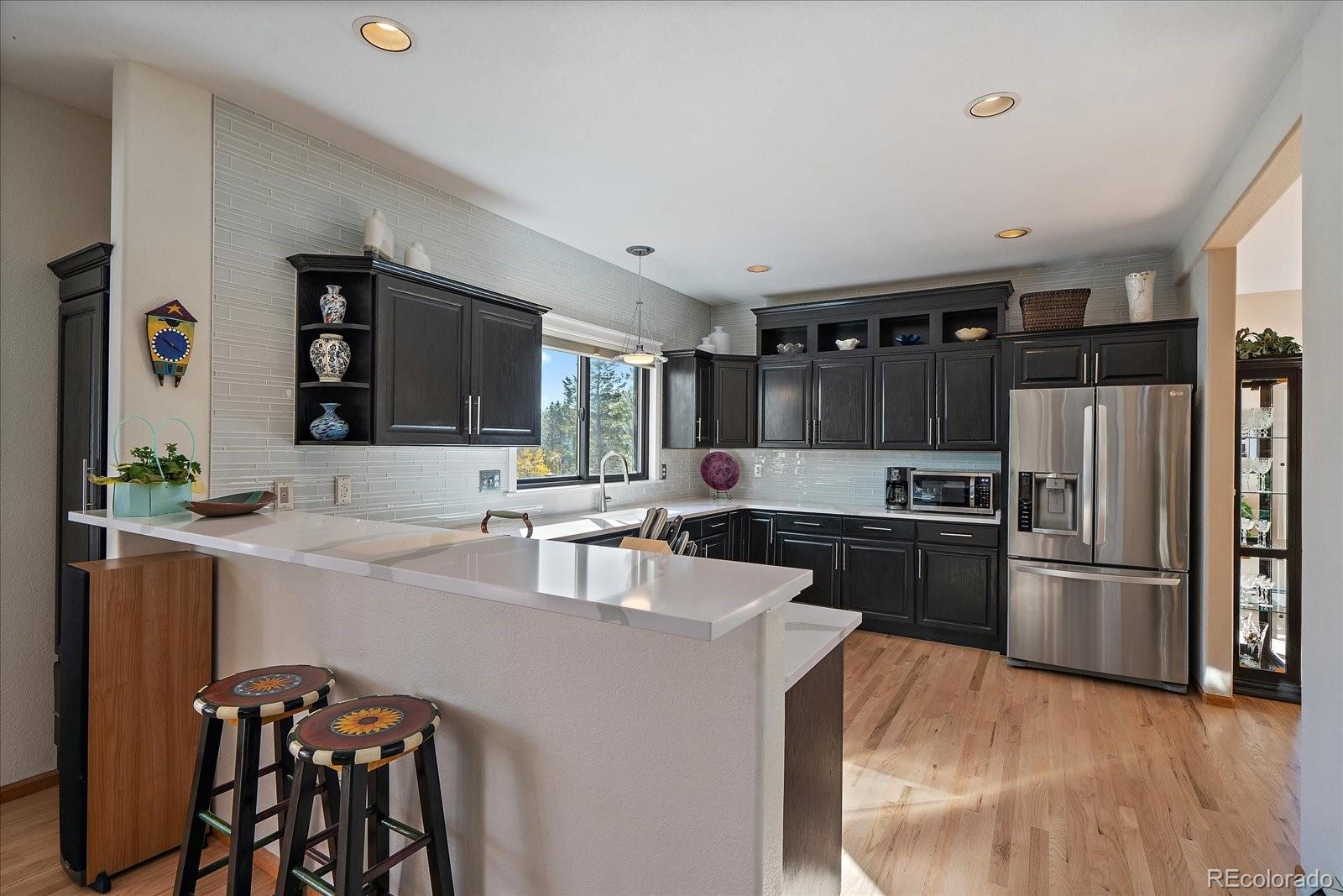 31518 Niakwa Road Evergreen, CO 80439 - Photo 5 of 48 a kitchen with granite countertop a refrigerator stove microwave and cabinets
