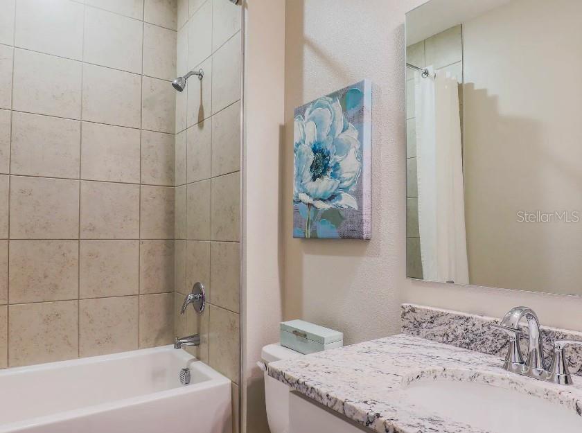 4021 Maggie Loop Lakeland, FL 33813 - Photo 22 of 29 a bathroom with a granite countertop sink a mirror and shower