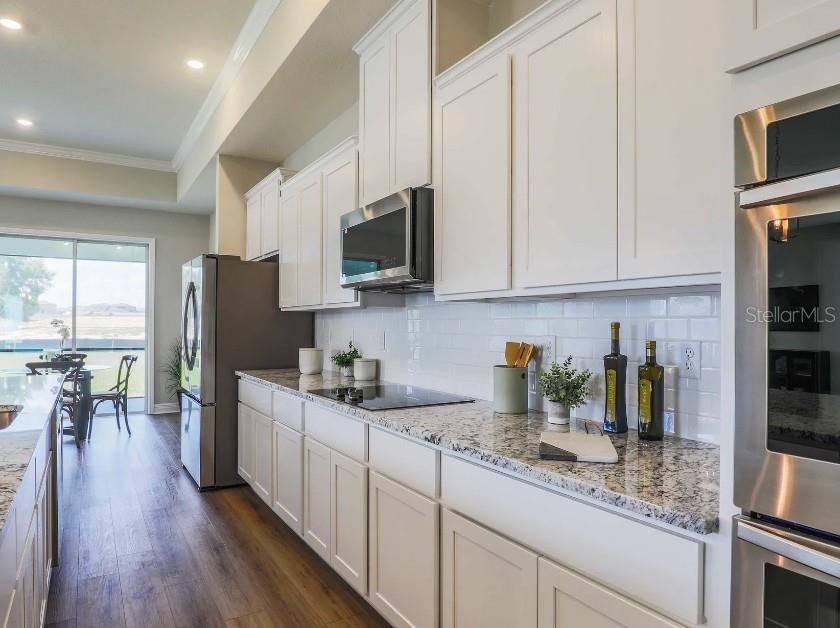 4021 Maggie Loop Lakeland, FL 33813 - Photo 10 of 29 a kitchen with stainless steel appliances granite countertop a refrigerator a stove top oven a sink dishwasher and white cabinets with wooden floor