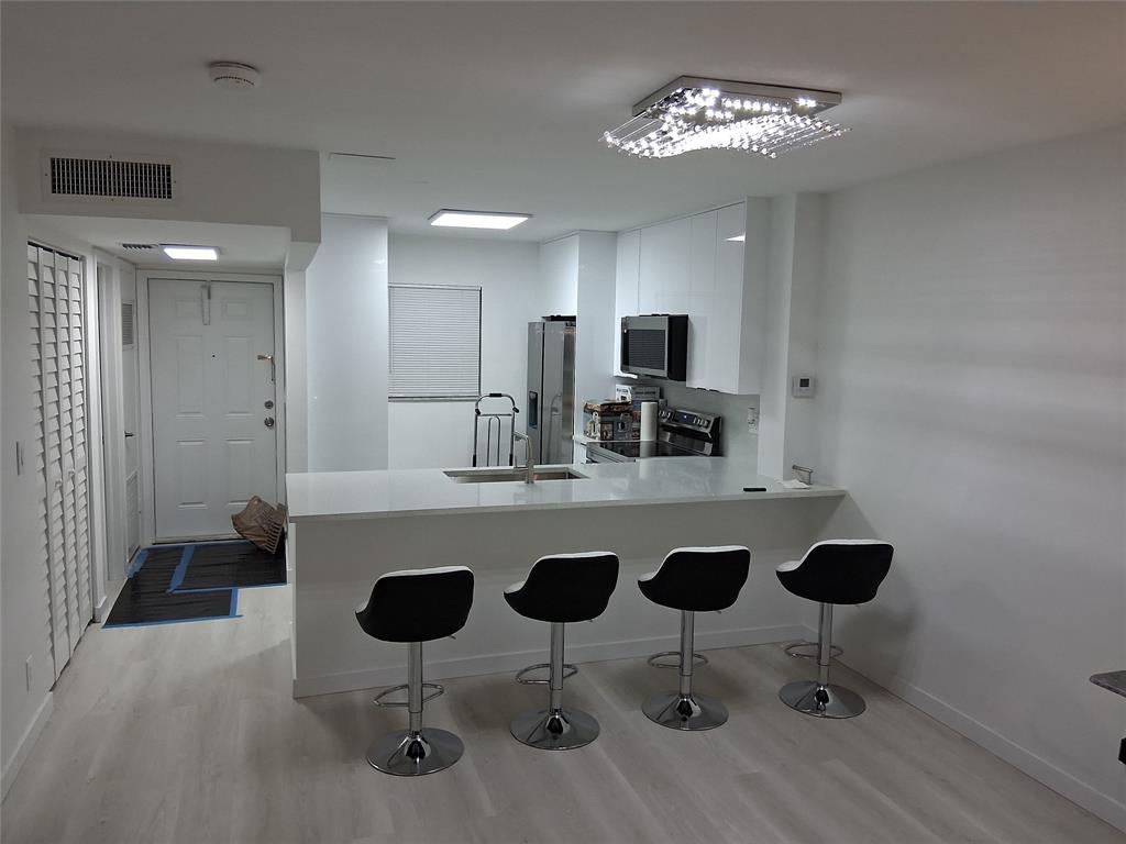 100 Berkley Road, Unit 105 Hollywood, FL 33024 - Photo 2 of 18 a kitchen with stainless steel appliances granite countertop a dining table chairs and granite counter tops