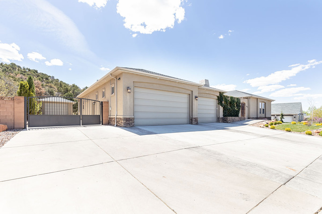 888 East Fiddlers Canyon Road Cedar City, UT 84721 - Photo 4 of 74 View of front of home with a gate, concrete driveway, a garage, stone siding, and stucco siding