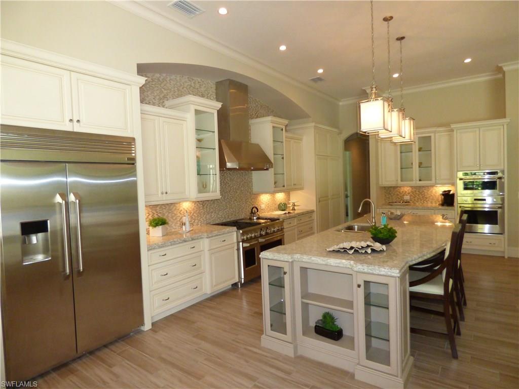 6376 Burnham Road Naples, FL 34119 - Photo 4 of 23 a kitchen with stainless steel appliances kitchen island granite countertop a stove a sink dishwasher and a refrigerator with wooden floor