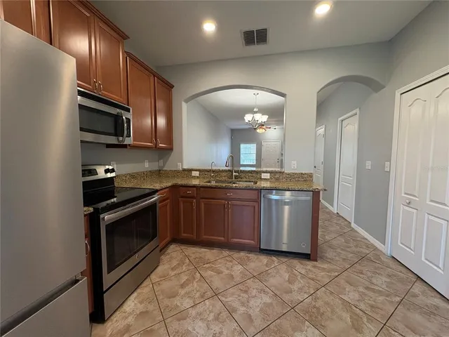 a kitchen with stainless steel appliances granite countertop a stove a sink and a microwave