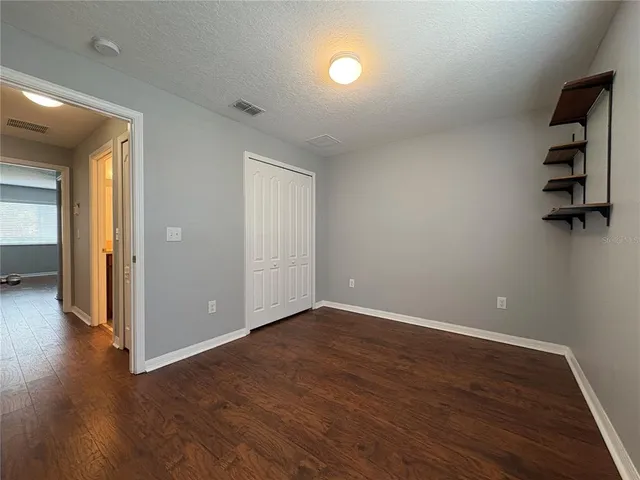 an empty room with wooden floor cabinet and windows