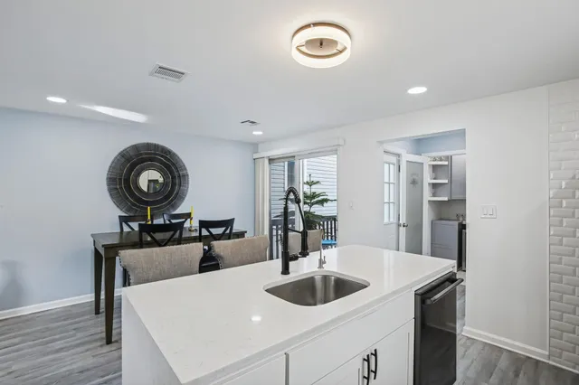 a kitchen with stainless steel appliances granite countertop a stove top oven a dining table and chairs with wooden floor