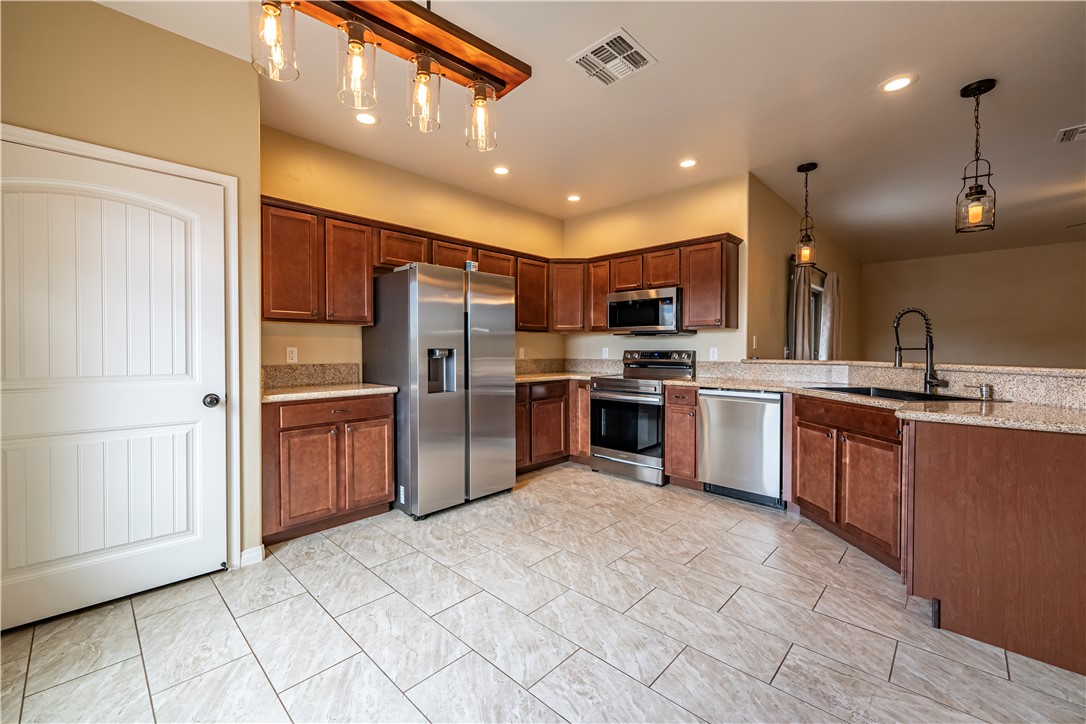 3546 North Kenneth Road Kingman, AZ 86409 - Photo 2 of 35 The kitchen features tile flooring, brown cabinetry, granite countertops, and stainless steel appliances, including a refrigerator, microwave, oven, and dishwasher