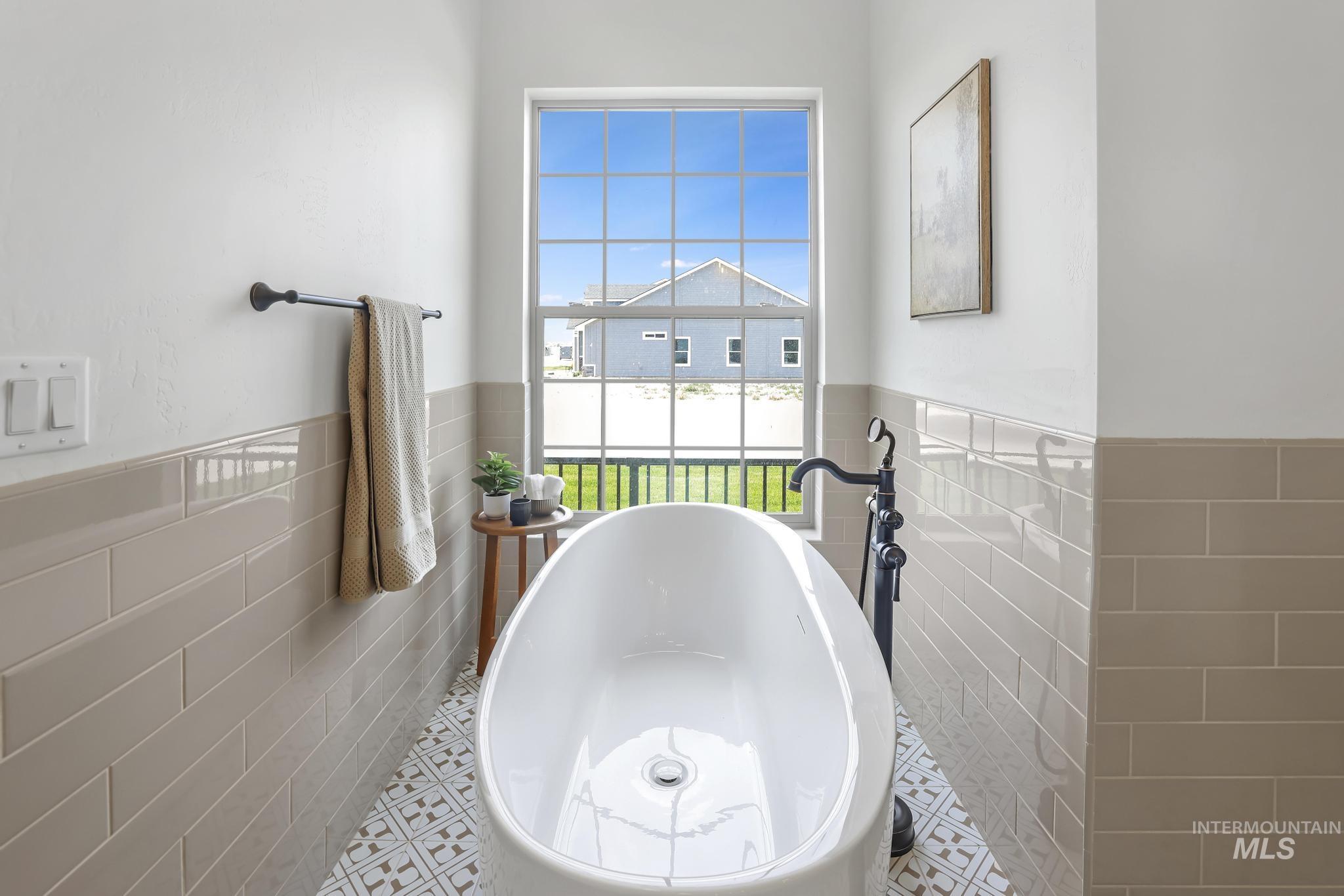 866 Quartz Road Kimberly, ID 83341 - Photo 24 of 48 Freestanding soaking tub with a floor-mounted matte black faucet, set against a backdrop of light grey subway tile wainscoting and a patterned floor tile