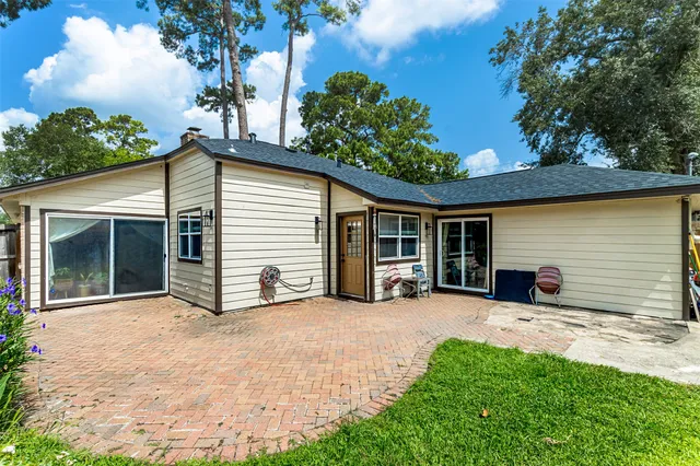 a view of a house with a yard plants and a large tree