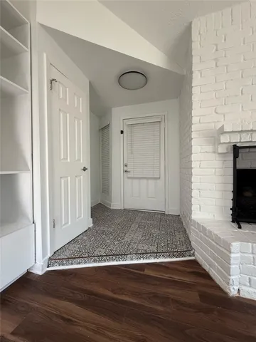 a view of an empty room with wooden floor and a fireplace