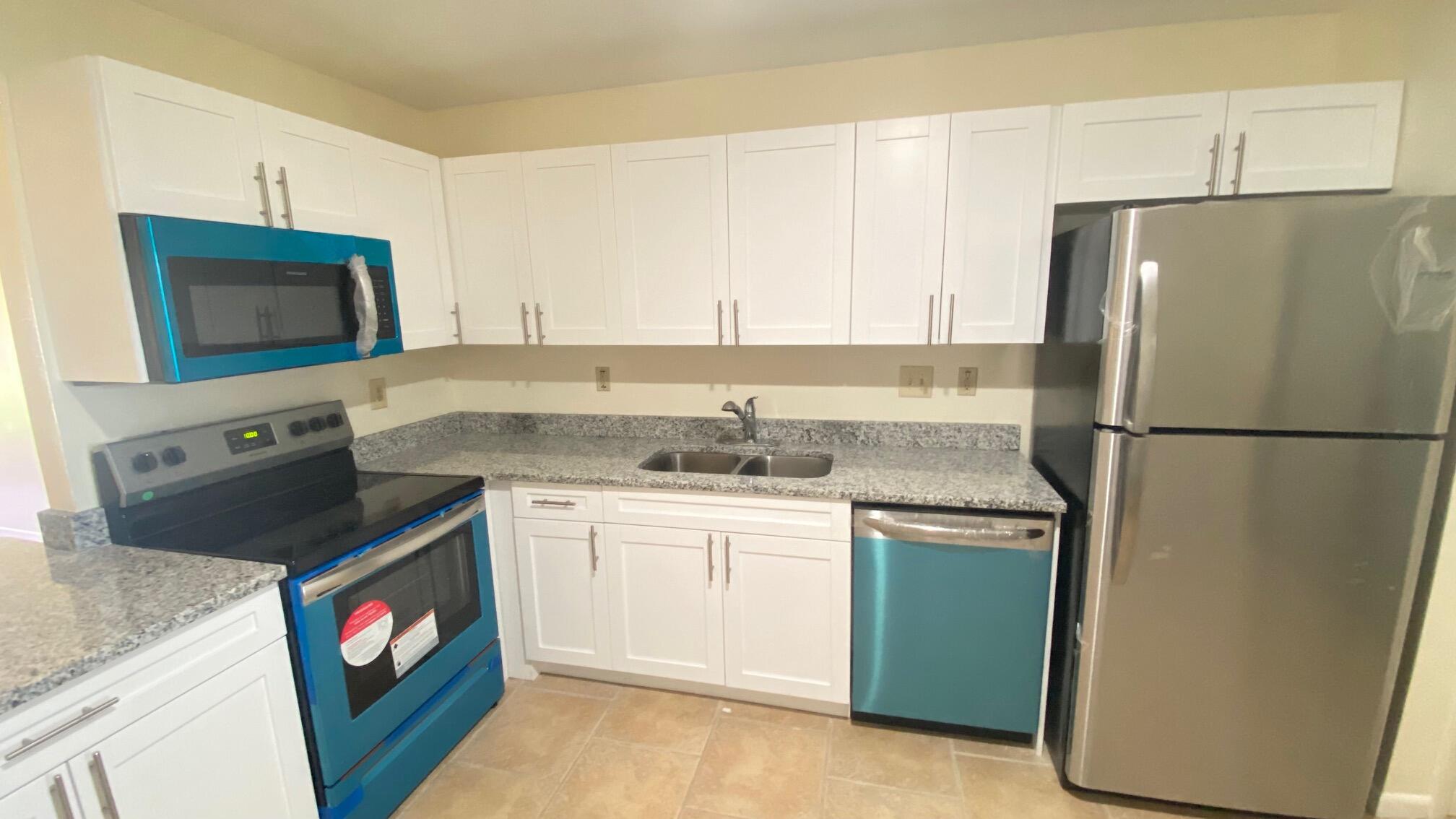5935 Forest Hill Boulevard, Unit 8 West Palm Beach, FL 33415 - Photo 1 of 6 a kitchen with stainless steel appliances granite countertop a refrigerator a stove a sink and a microwave