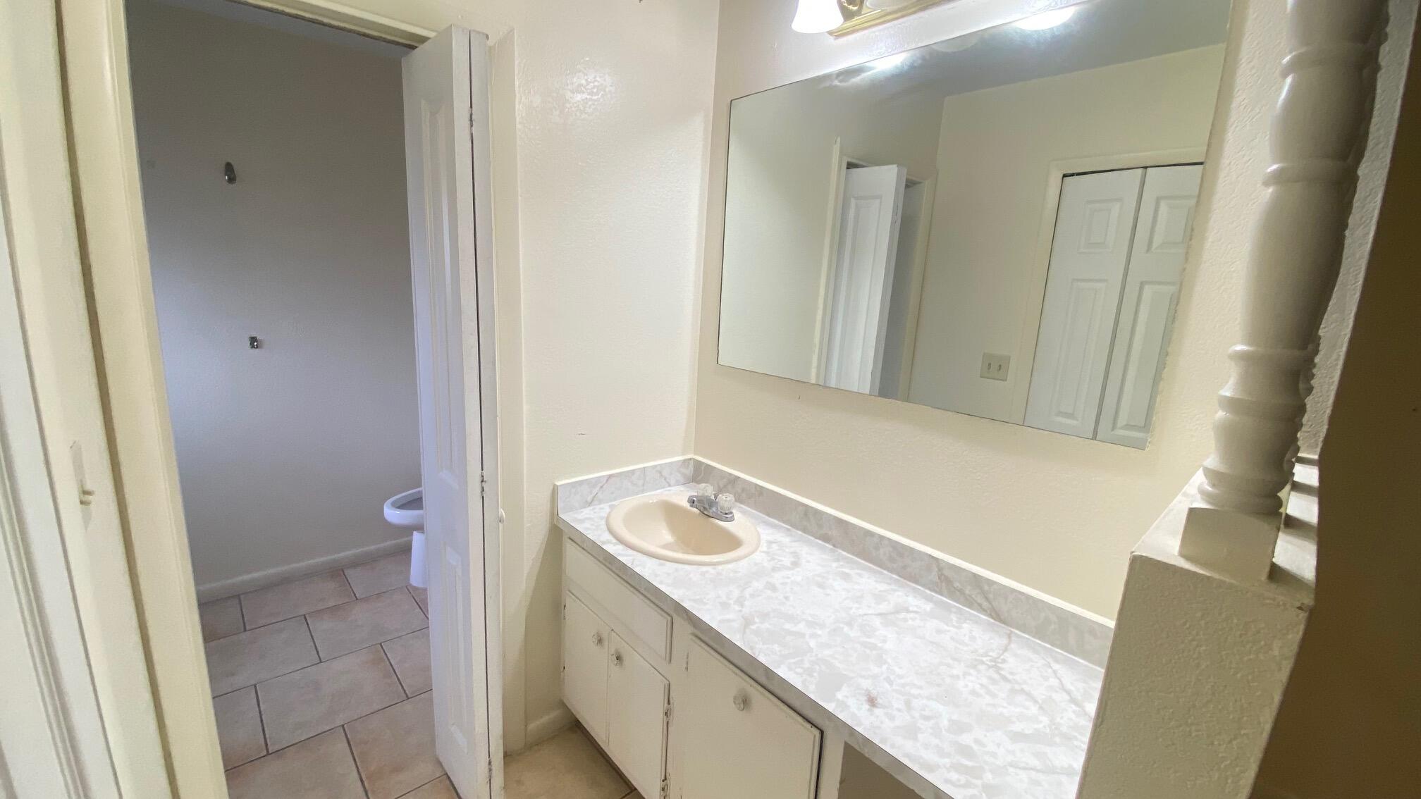 5935 Forest Hill Boulevard, Unit 8 West Palm Beach, FL 33415 - Photo 3 of 6 a bathroom with a granite countertop sink and a mirror
