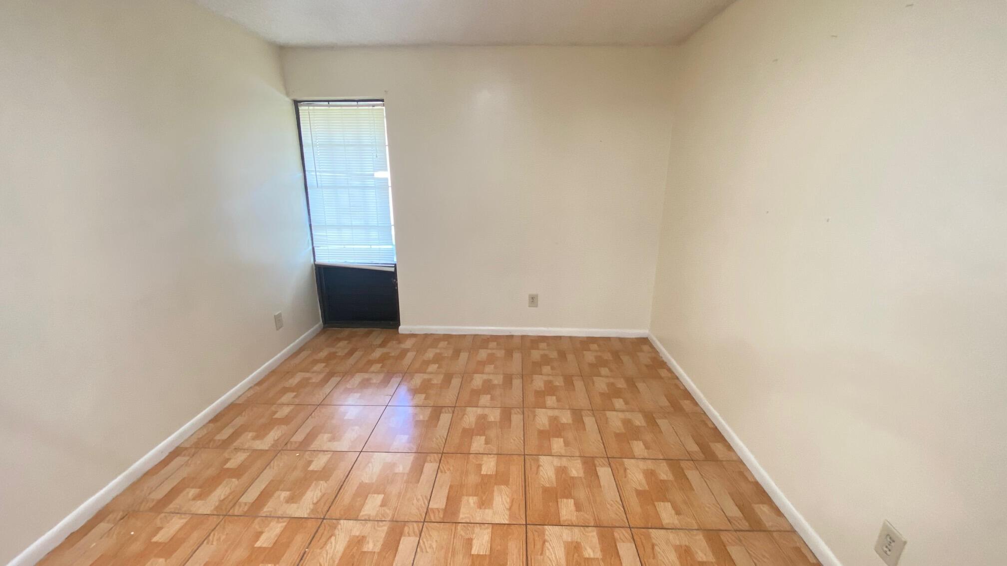 5935 Forest Hill Boulevard, Unit 8 West Palm Beach, FL 33415 - Photo 4 of 6 a view of a room with wooden floor and white walls