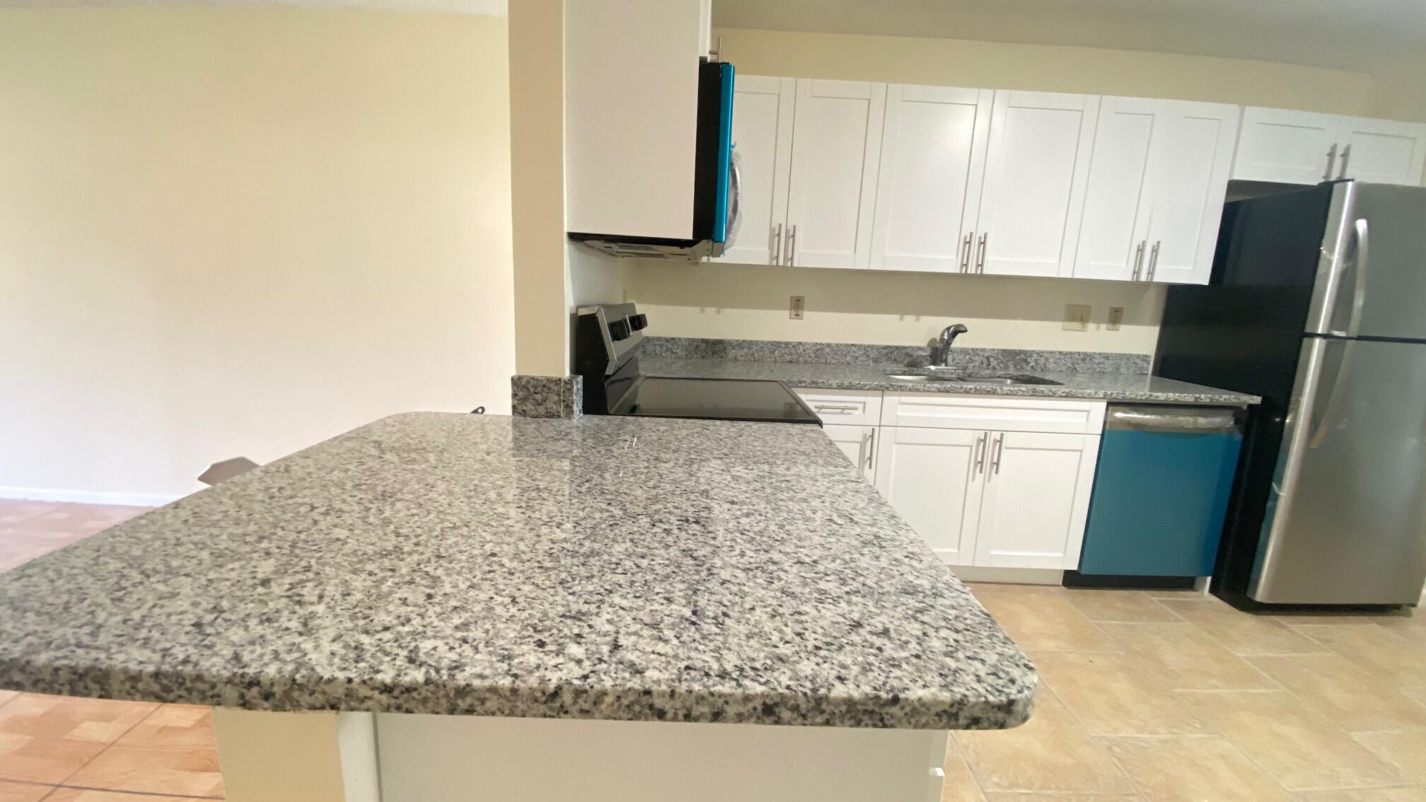 5935 Forest Hill Boulevard, Unit 8 West Palm Beach, FL 33415 - Photo 5 of 6 a kitchen with stainless steel appliances granite countertop a sink stove and refrigerator