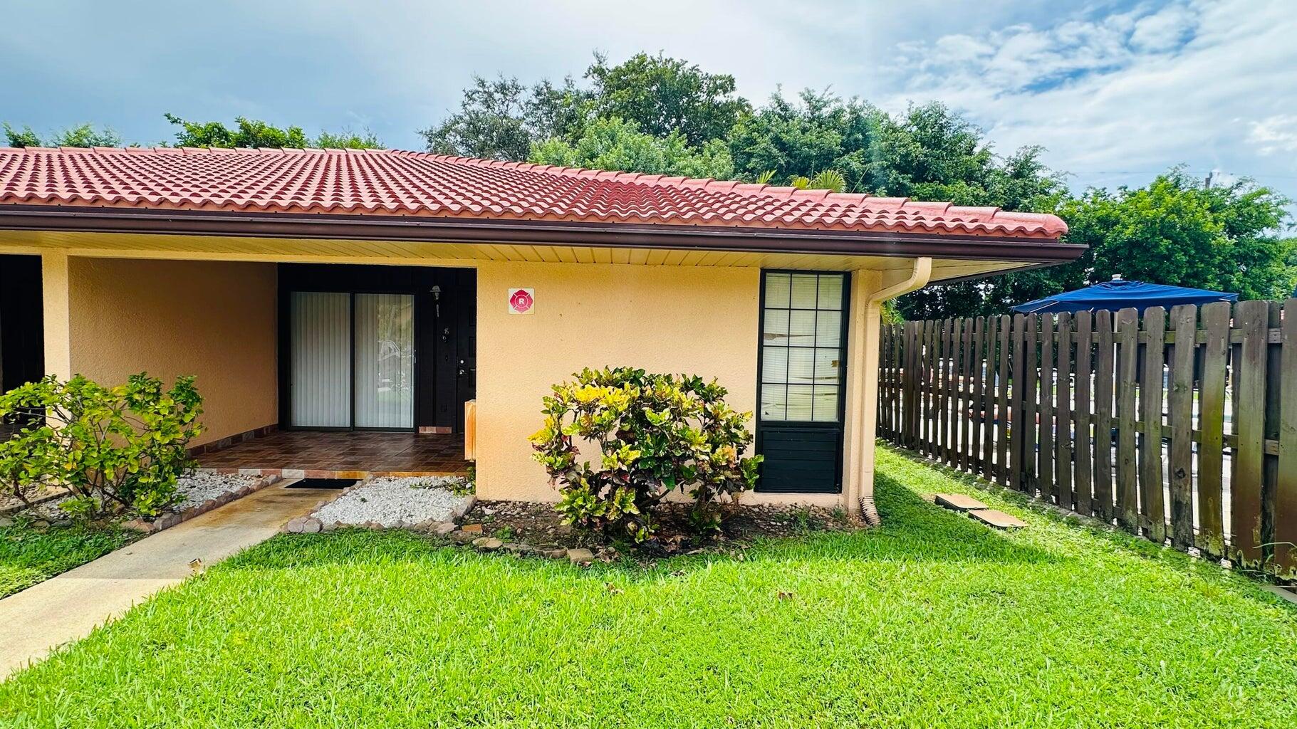 5935 Forest Hill Boulevard, Unit 8 West Palm Beach, FL 33415 - Photo 6 of 6 a view of a house with a small yard and wooden fence
