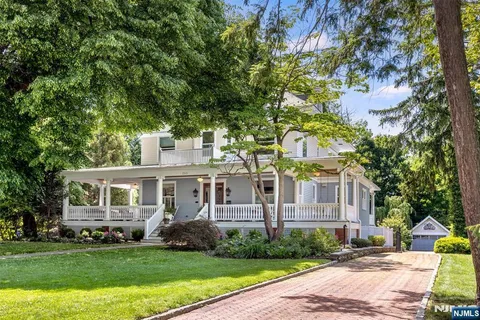 a view of a white house with a big yard and large trees