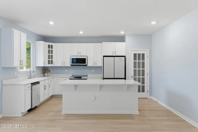a large white kitchen with kitchen island a sink a stove and a refrigerator