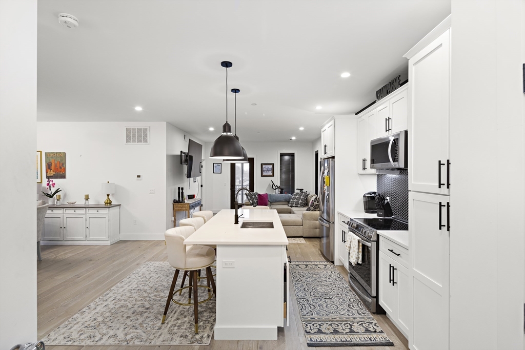 68 Armandine Street, Unit 3 Boston, MA 02124 - Photo 2 of 23 a large white kitchen with stainless steel appliances kitchen island granite countertop a large counter top space a sink a stove and a refrigerator