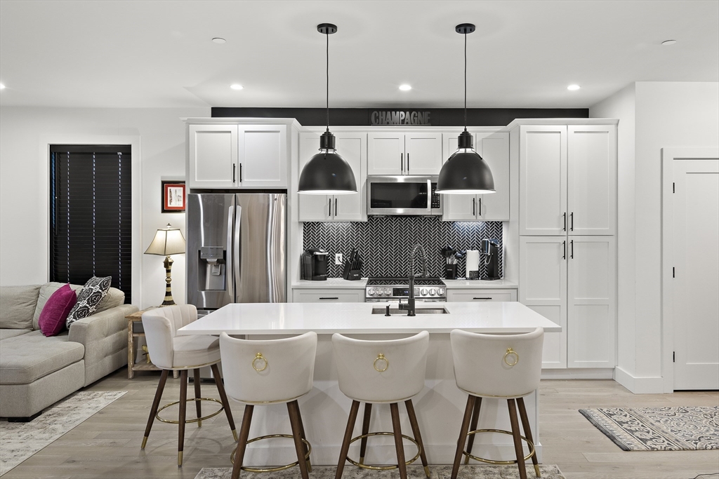 68 Armandine Street, Unit 3 Boston, MA 02124 - Photo 3 of 23 a kitchen with stainless steel appliances kitchen island granite countertop a dining table chairs and a refrigerator