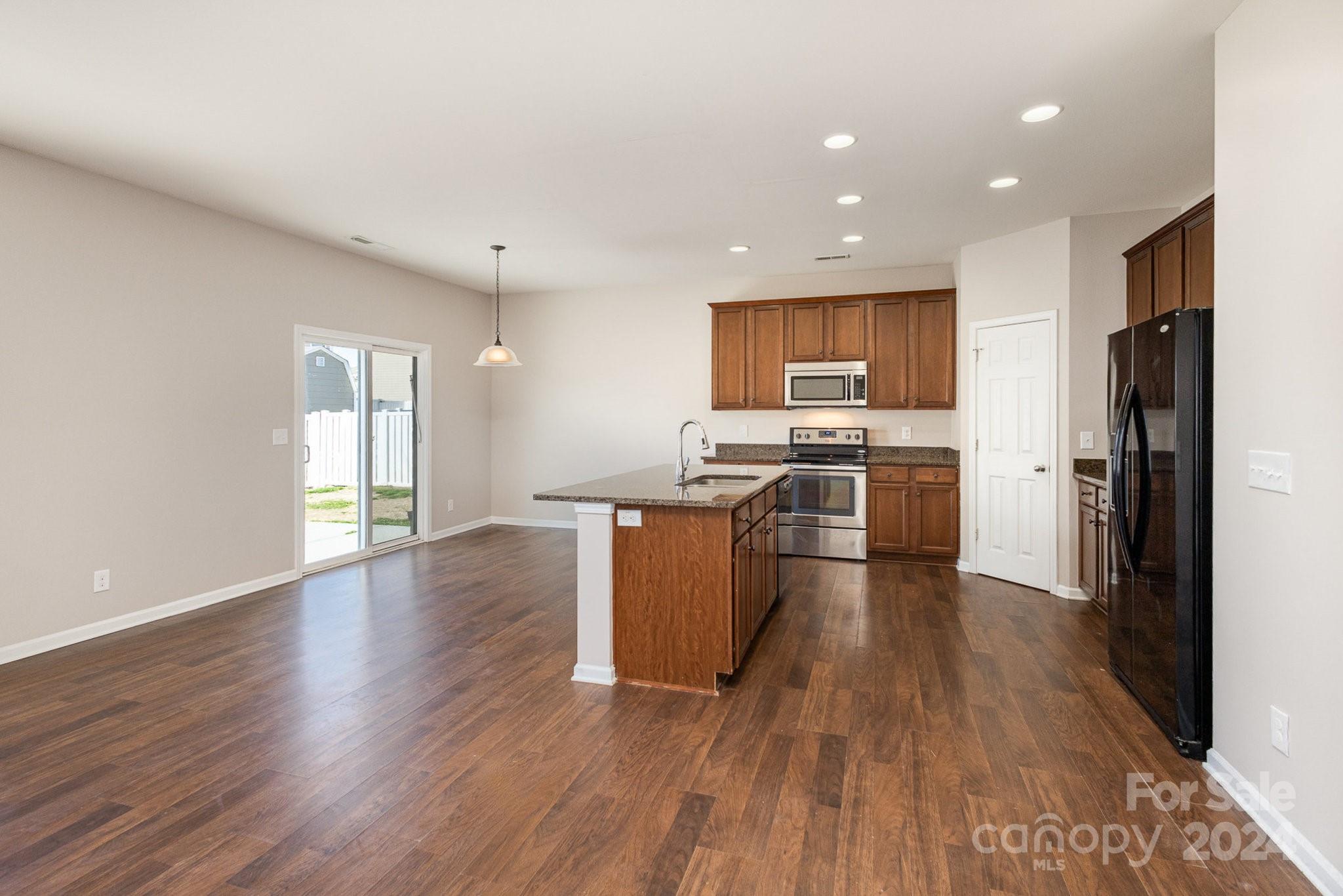 1005 Green Terra Road Indian Trail, NC 28079 - Photo 5 of 19 a kitchen with stainless steel appliances granite countertop a stove top oven a refrigerator with island and wooden floor