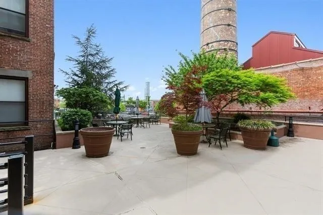 a view of a patio with a table and chairs under an umbrella with a barbeque