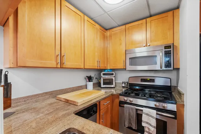 a kitchen with stainless steel appliances granite countertop a stove a sink and a microwave