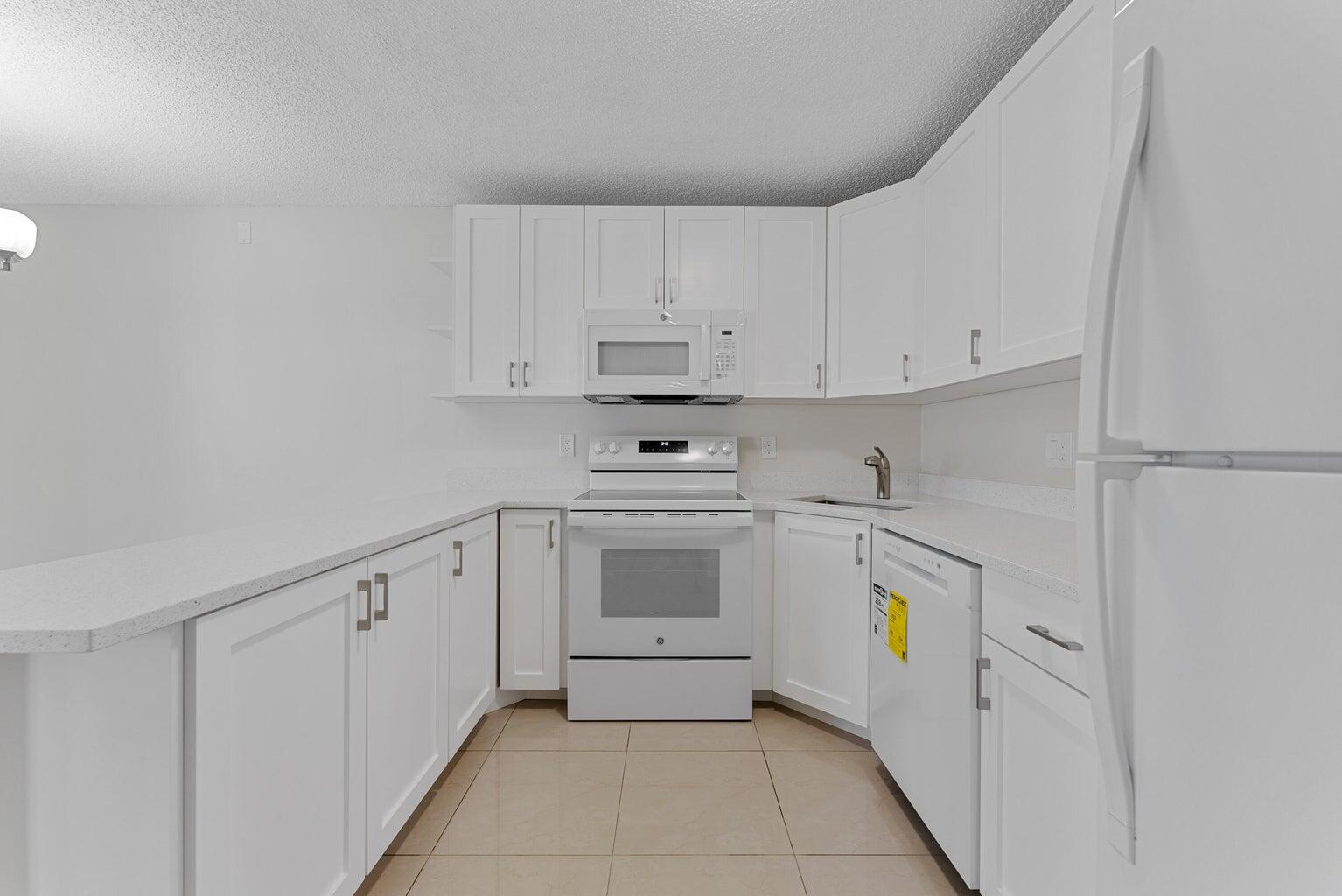 537 Shady Pine Way Greenacres, FL 33415 - Photo 13 of 21 a kitchen with white cabinets and white appliances