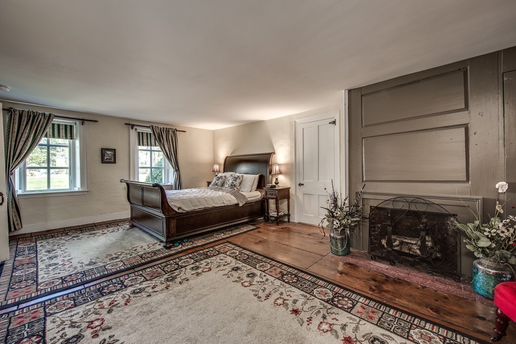 5 East Main Street Hopkinton, MA 01748 - Photo 8 of 20 a bedroom with a bed a fireplace and wooden floor