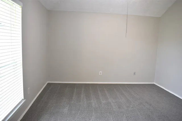 an empty room with chandelier fan and windows