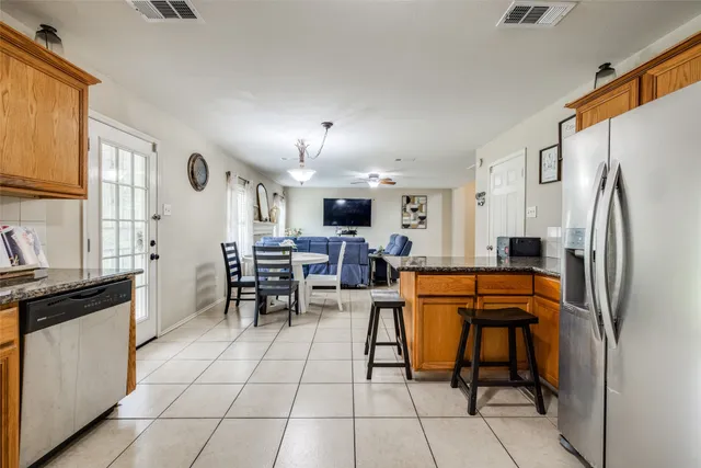 a kitchen with stainless steel appliances kitchen island granite countertop dining table chair and a refrigerator