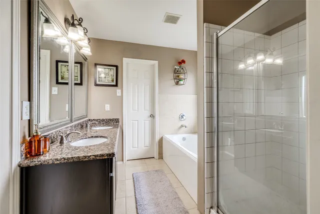 a bathroom with a granite countertop sink a mirror a bathtub and shower