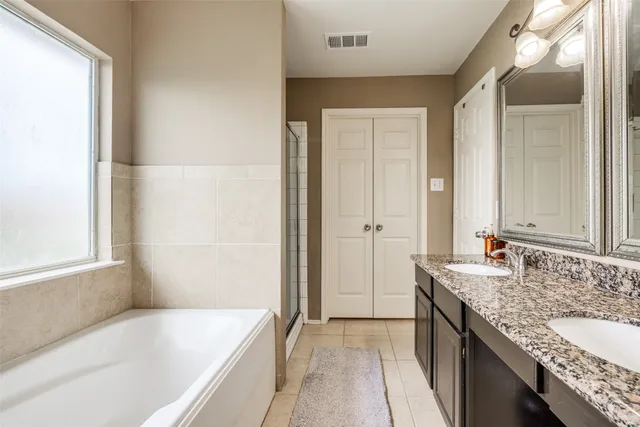 a bathroom with a granite countertop tub sink and mirror