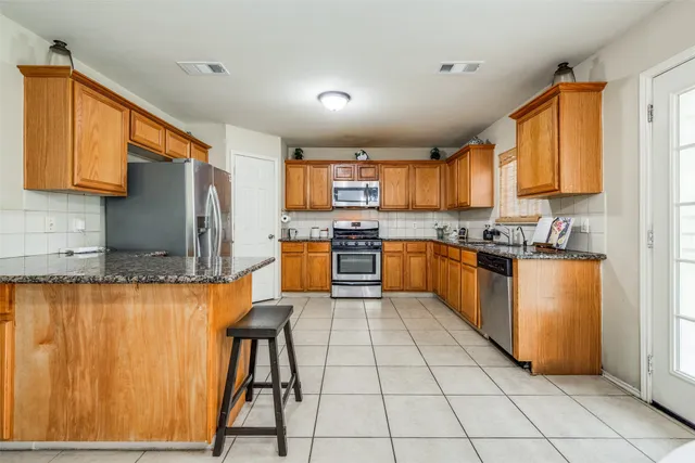 a kitchen with stainless steel appliances granite countertop wooden cabinets a stove top oven a sink and dishwasher