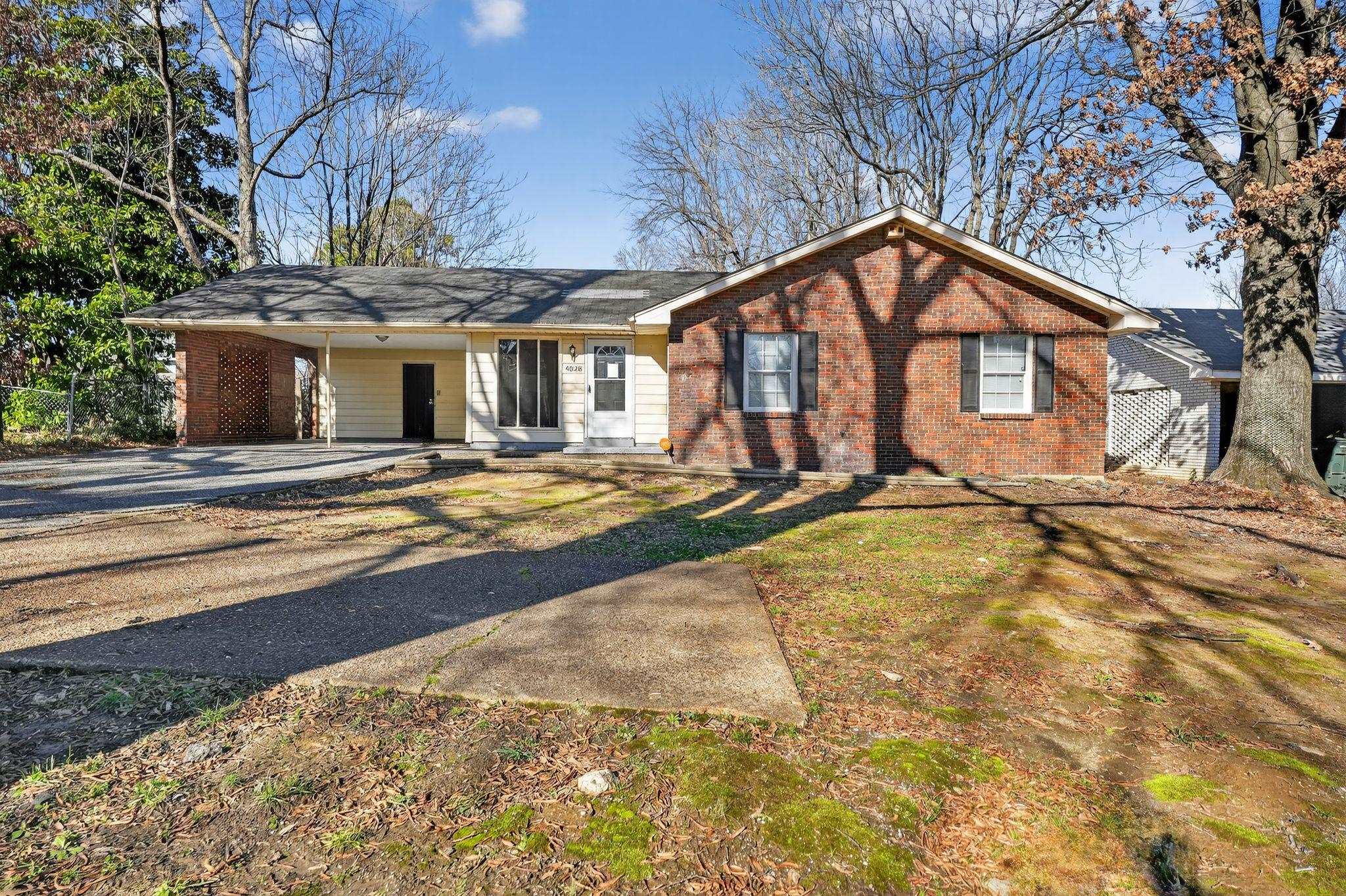 Ranch-style home with an attached carport, driveway, brick siding, and covered porch