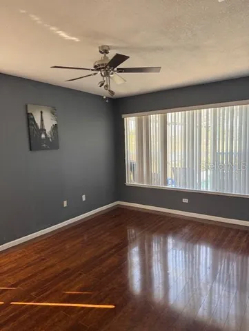 a view of an empty room with wooden floor and a window