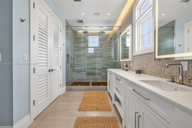 a bathroom with a double vanity sink a toilet a shower and a mirror